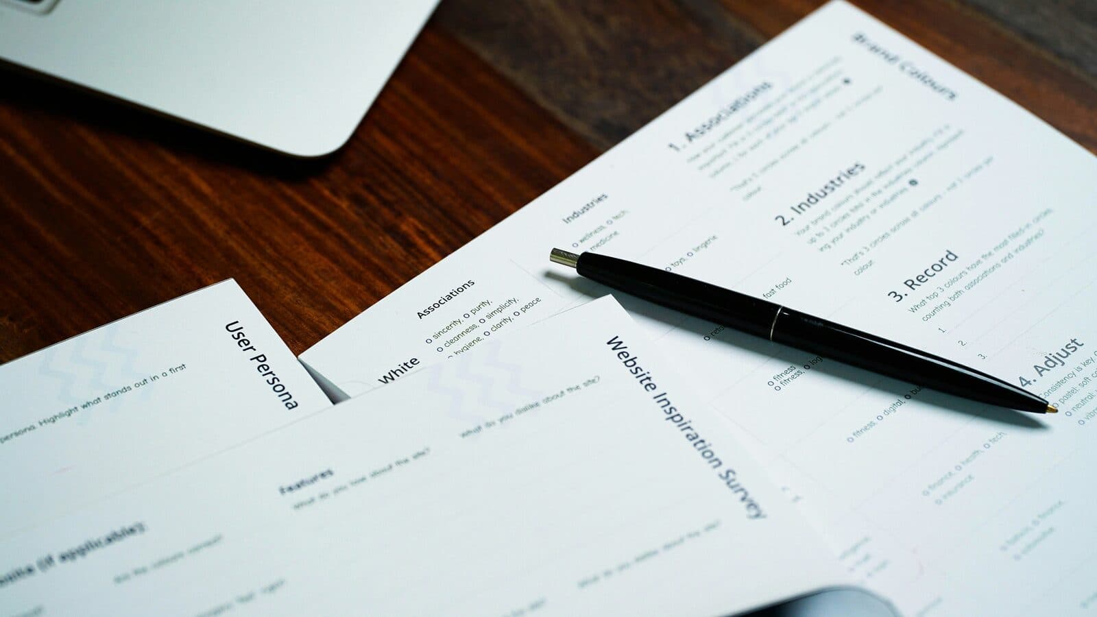 Printed forms and a pen laid out across a wooden desk