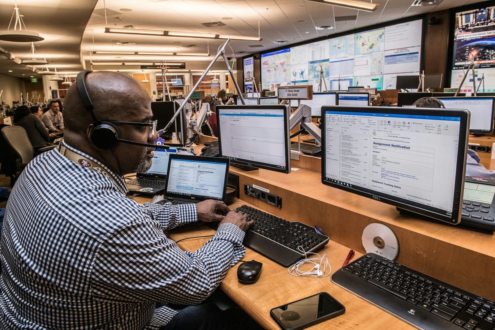 An operations team member in a headset working across several monitors in a control room